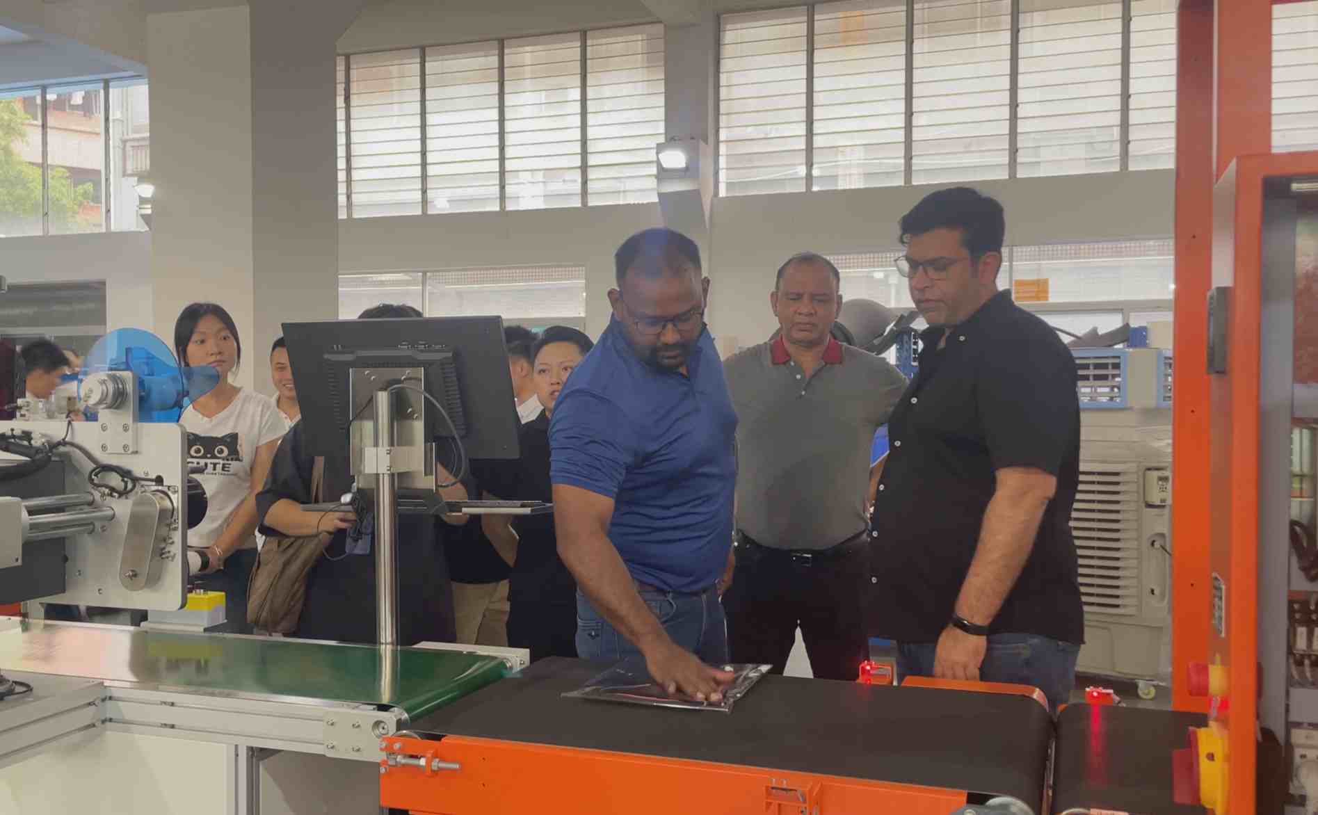 UBL’s Indian clients inspecting a bagging machine in the production workshop: The clients are observing and interacting with the bagging equipment, with UBL team members on-site assisting and explaining the operation