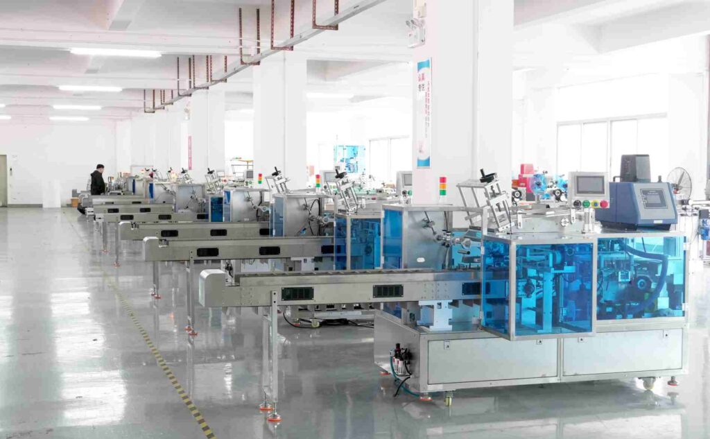 UBL’s glue-spray cartoning machines neatly arranged in the production workshop: The stainless-steel and blue-enclosed glue-spray cartoning equipment is lined up orderly, ready for quality inspection and shipment