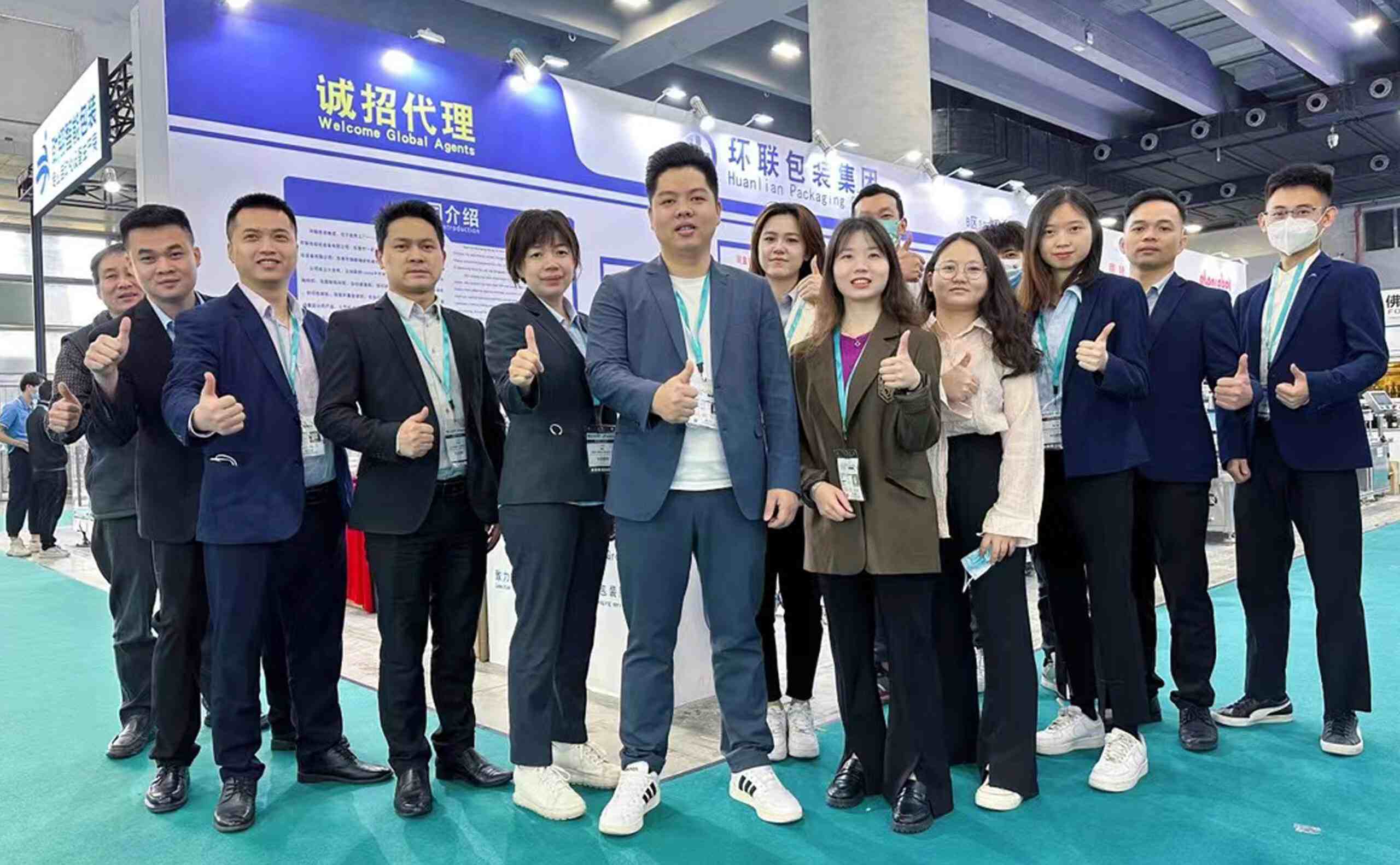 "UBL (Huanlian Packaging Group) team at a trade show booth featuring 'Welcome Global Agents' signage: Our expanded team posing at the exhibition stand, showcasing the company’s global agent recruitment initiative alongside packaging solutions"