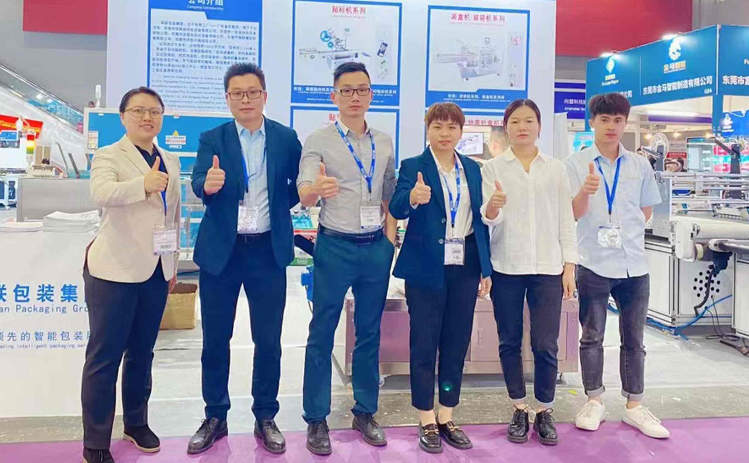 UBL (Huanlian Packaging Group) team at a trade show booth: Displaying packaging equipment series (labeling machines, cartoning machines) alongside company introduction materials, with staff giving thumbs-up at the exhibition stand