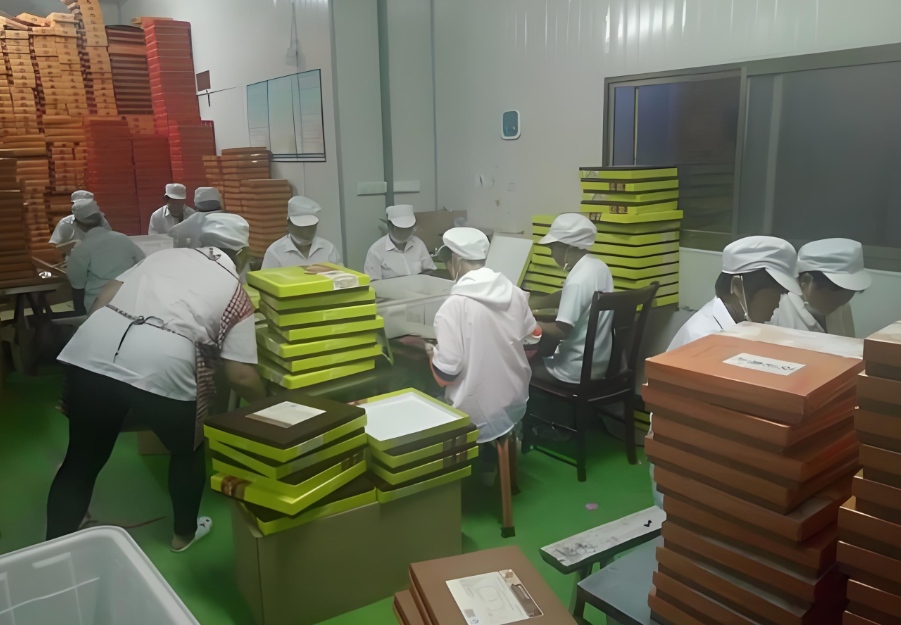 Workers manually folding and assembling gift boxes in a factory – underscoring the slow pace of manual box preparation during peak seasons, and the value of high-speed automatic gift box folding and forming machine (a specialized packaging equipment) for consistent, efficient product packaging