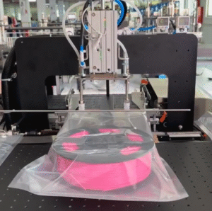 High-speed filament vacuum packaging machine completing the vacuum seal process for a pink 3D printing filament spool, delivering tight, airtight packaging to prevent moisture absorption and ensure print quality.