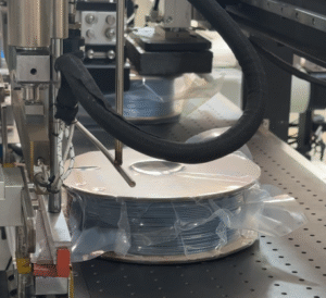 Spool Packaging Machine sealing a 3D filament spool in a plastic bag during the packaging process