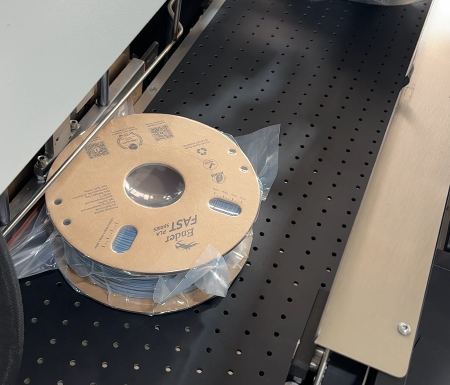 Spool Packaging Machine in operation, bagging a 3D printing filament spool on the conveyor line