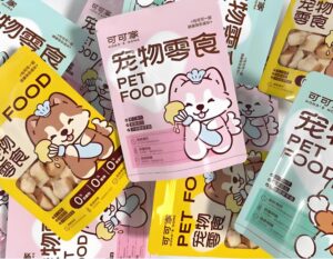 Colorful small batch pet product packaging bags for snacks, featuring cute cartoon dog illustrations in pink, yellow and light blue. High-quality custom packaging for small batch pet food & treats, showcasing brand identity for pet snacks.