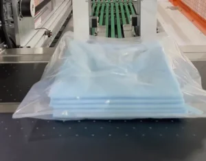 Stacked blue protective gowns neatly bagged by UBL automatic garment packaging machine, ready for sealing