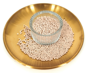 Light pink spherical molecular sieve desiccant beads, molecular sieve for 3D printing filament packaging piled inside glass cup on golden metal plate
