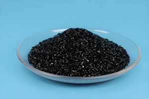 Black plastic desiccant particles, desiccant for filament packaging piled in transparent glass dish against light blue background