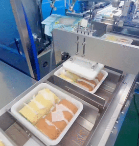 The arranged Swiss rolls are being pushed into cartons and sealed by UBL cake cartoning machine.