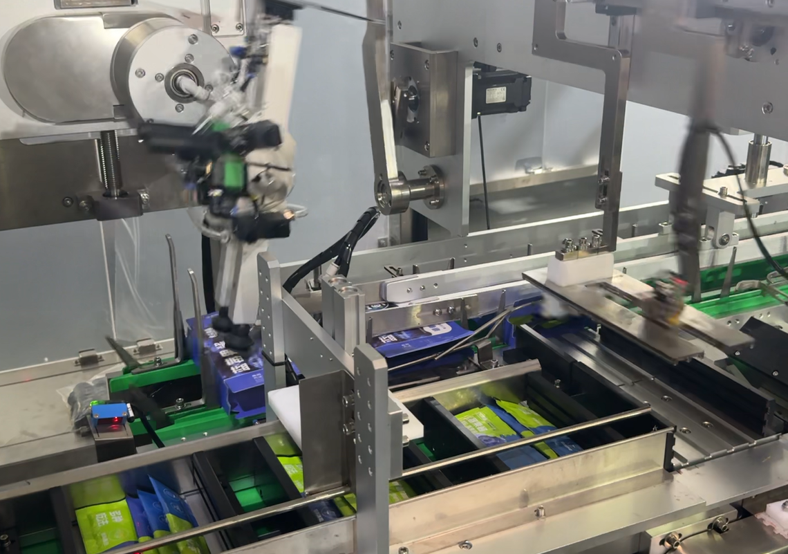 Automatic UBL food cartoner machine running, filling individual blueberry sauce stick packs into folded cardboard boxes