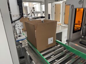 Case packer machine in operation, erecting cartons, ready to load products into cardboard boxes
